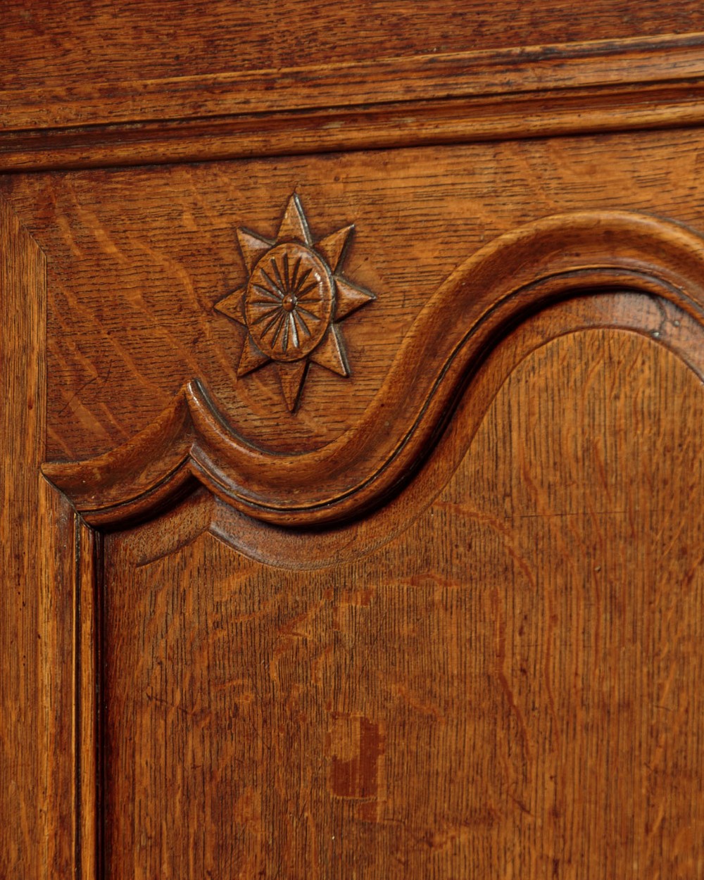 An 18th-century French provincial oak housekeepers cupboard featuring two upper and two lower moulded panel doors with carved star motifs and cabriole feet. View X