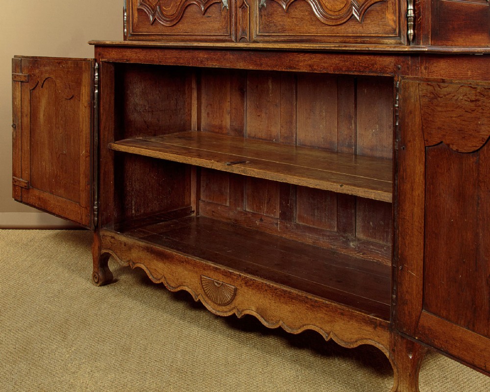 An 18th-century French provincial oak housekeepers cupboard featuring two upper and two lower moulded panel doors with carved star motifs and cabriole feet. View XI