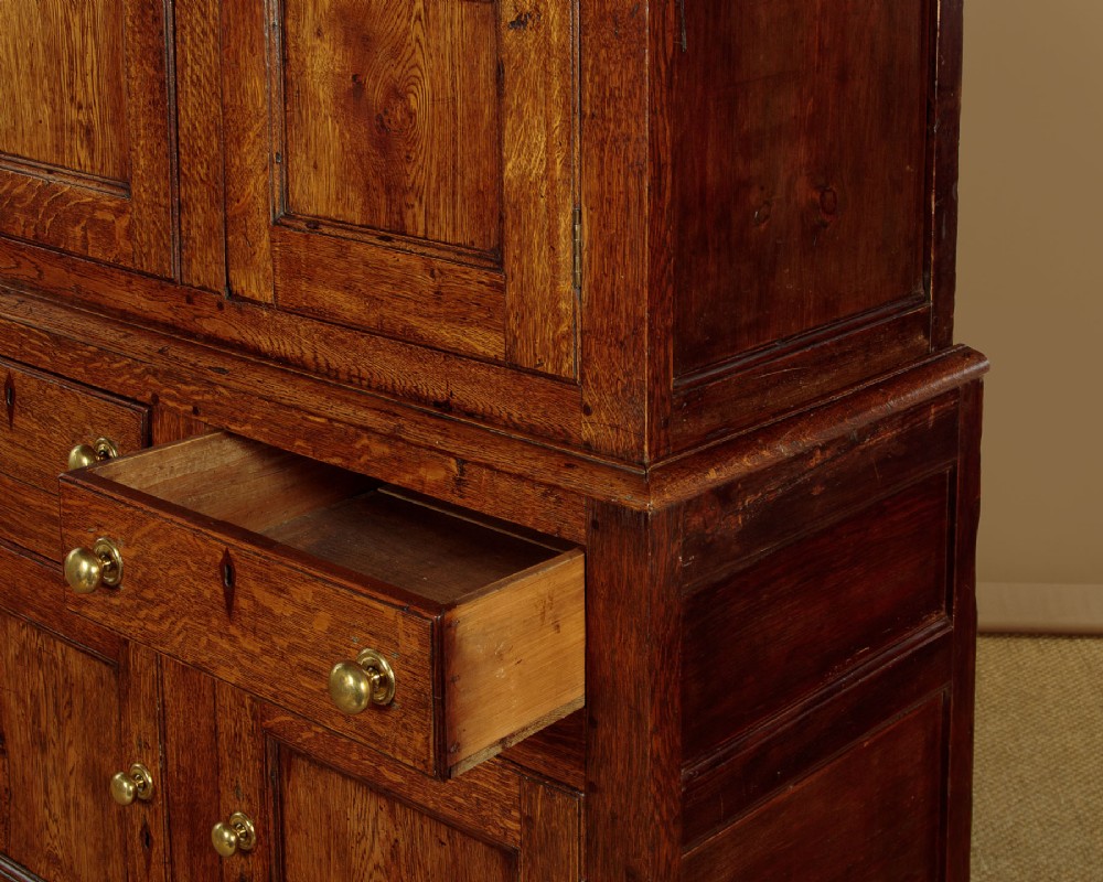 A two-part antique warm brown oak bread and cheese cupboard featuring upper doors with lattice ventilation fretwork over lower drawers and panelled cupboard doors. View X