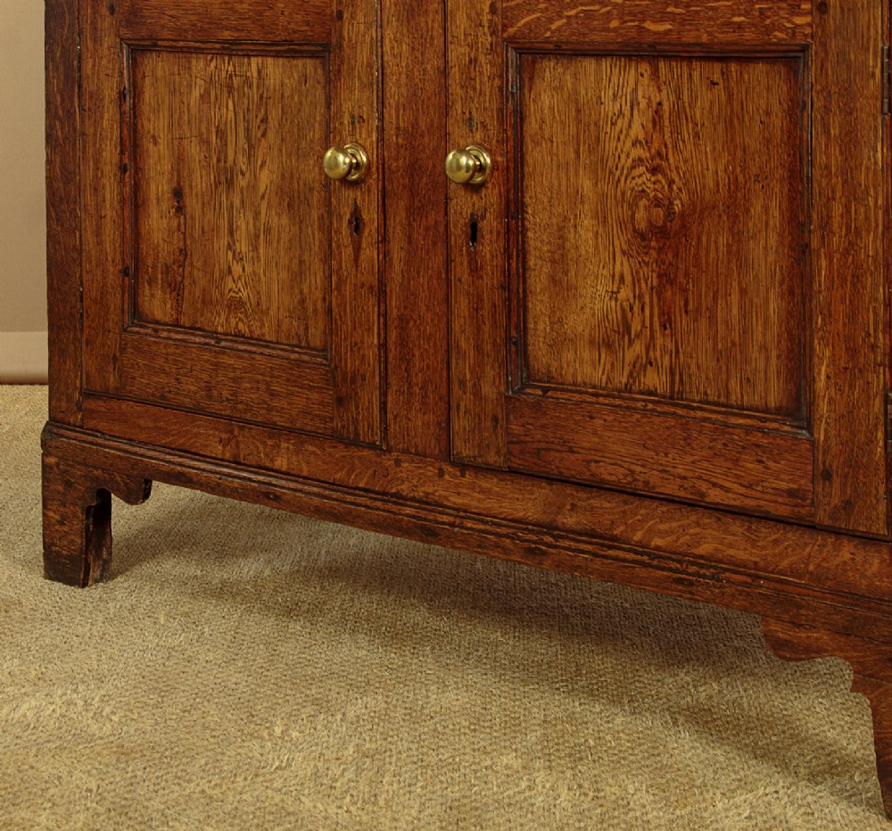 A two-part antique warm brown oak bread and cheese cupboard featuring upper doors with lattice ventilation fretwork over lower drawers and panelled cupboard doors. View XI