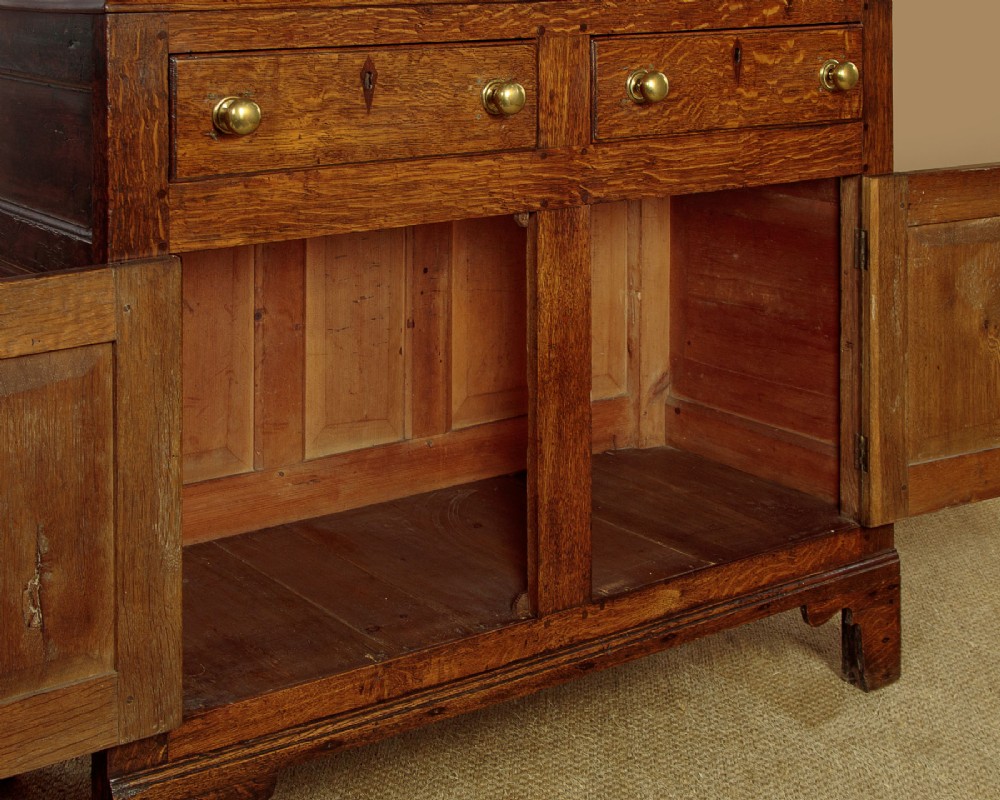 A two-part antique warm brown oak bread and cheese cupboard featuring upper doors with lattice ventilation fretwork over lower drawers and panelled cupboard doors. View XII