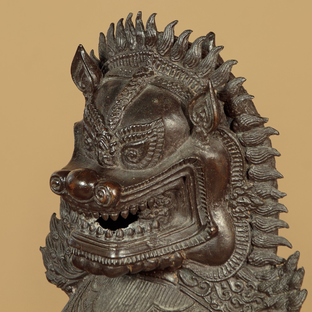 A pair of dark bronze temple lion statues sitting upright with intricate stylized manes and detailed ornamental chest bands. View IX