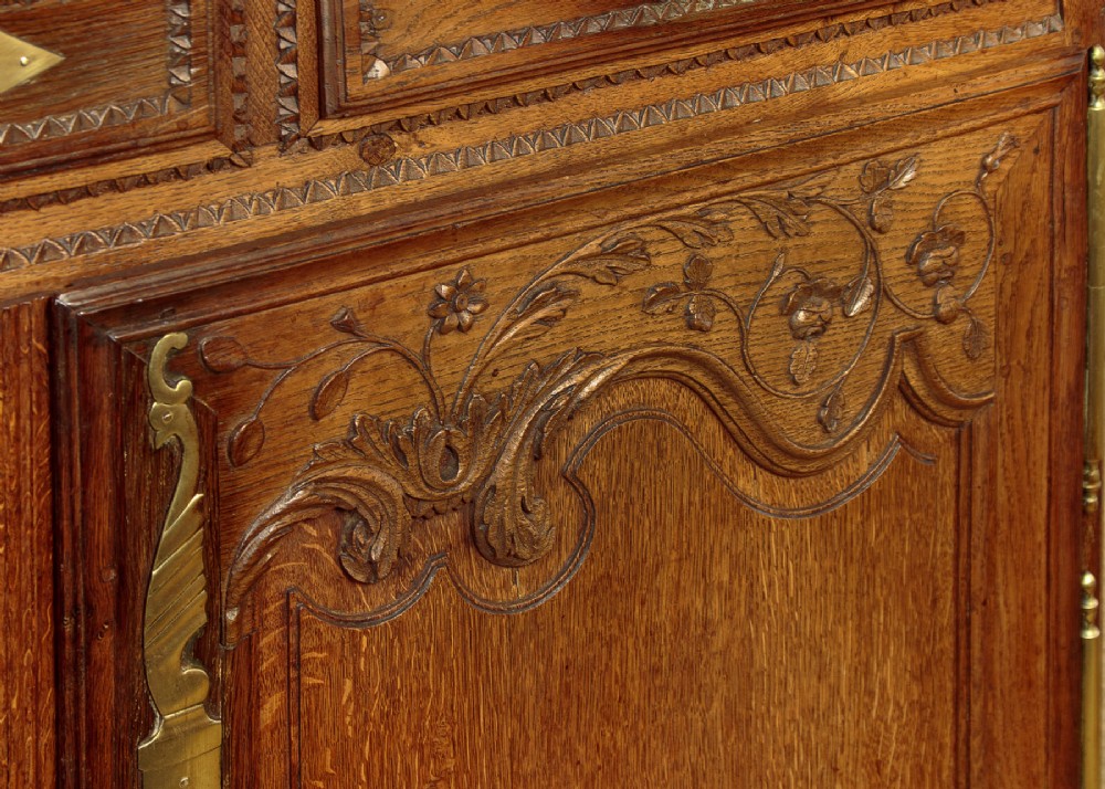 A late 18th-century French oak dresser base featuring two drawers above carved panelled cupboard doors with brass hardware. View IX