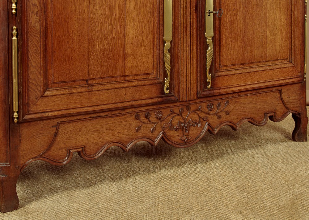 A late 18th-century French oak dresser base featuring two drawers above carved panelled cupboard doors with brass hardware. View XII