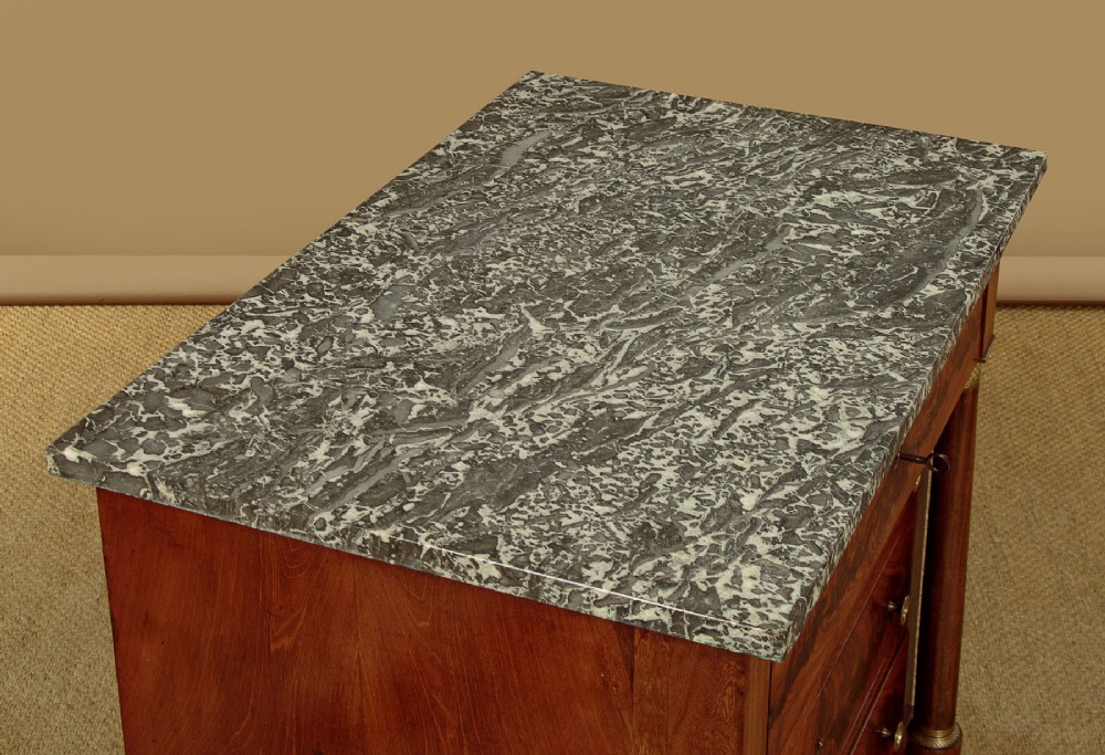 An Empire style mahogany chest of four drawers featuring a grey marble top, brass pull handles, and side column pillars. View IV