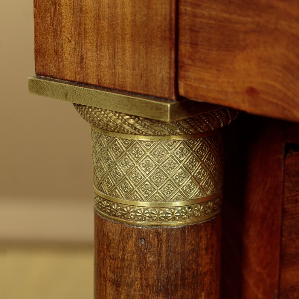 An Empire style mahogany chest of four drawers featuring a grey marble top, brass pull handles, and side column pillars. View IX