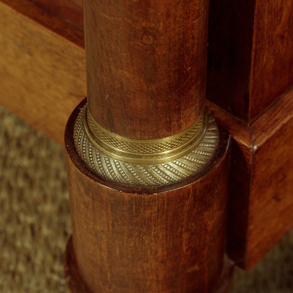 An Empire style mahogany chest of four drawers featuring a grey marble top, brass pull handles, and side column pillars. View X