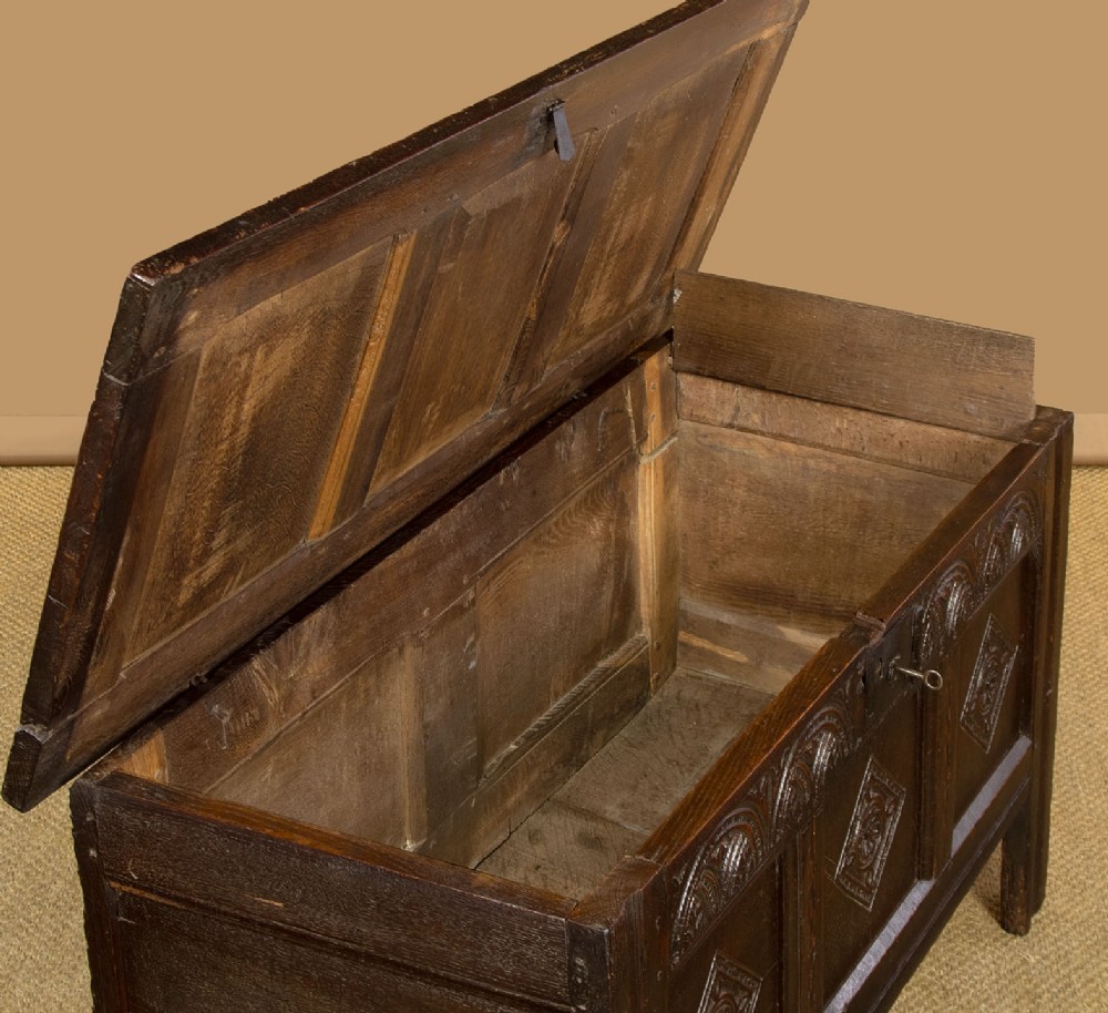 A dark carved oak 17th-century coffer featuring three lozenge-carved front panels, a lunette carved top rail, and a panelled hinged lid. View VI