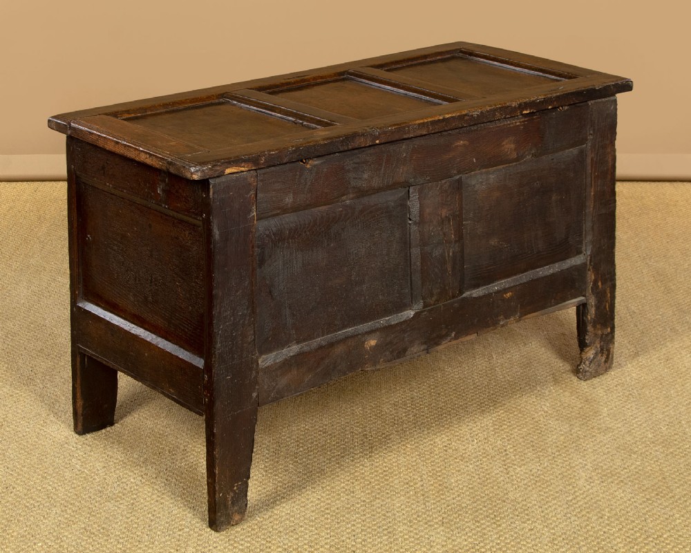 A dark carved oak 17th-century coffer featuring three lozenge-carved front panels, a lunette carved top rail, and a panelled hinged lid. View IX