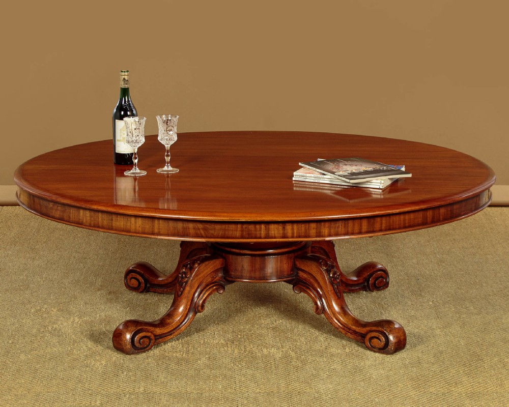 A large Victorian mahogany oval coffee table featuring a polished top, a deep apron, and a carved quadruped pedestal base with scroll feet. View II