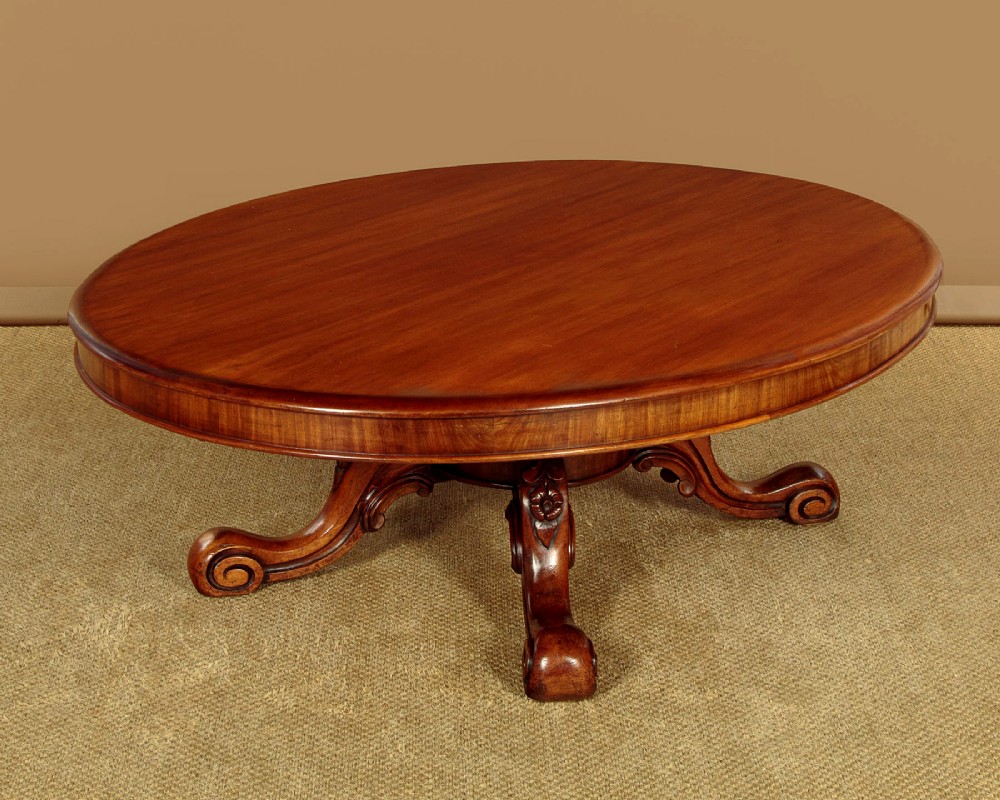 A large Victorian mahogany oval coffee table featuring a polished top, a deep apron, and a carved quadruped pedestal base with scroll feet. View III