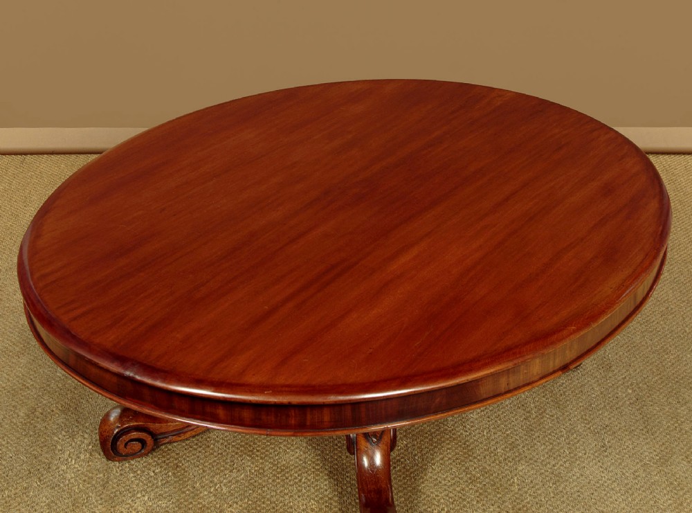 A large Victorian mahogany oval coffee table featuring a polished top, a deep apron, and a carved quadruped pedestal base with scroll feet. View IV