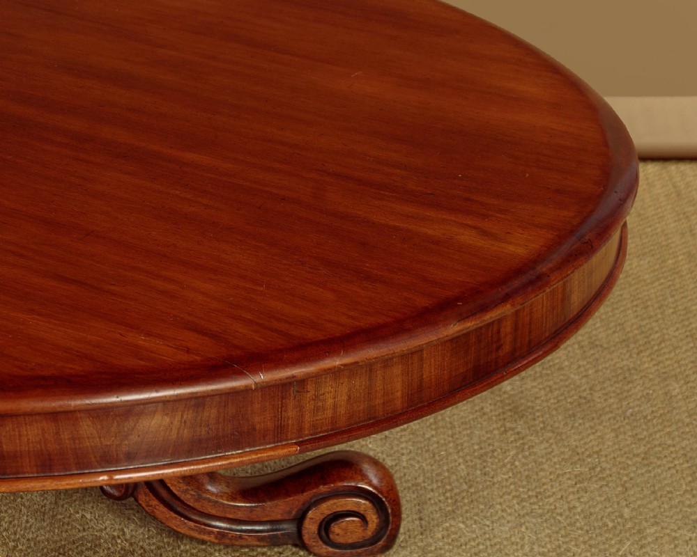 A large Victorian mahogany oval coffee table featuring a polished top, a deep apron, and a carved quadruped pedestal base with scroll feet. View VI