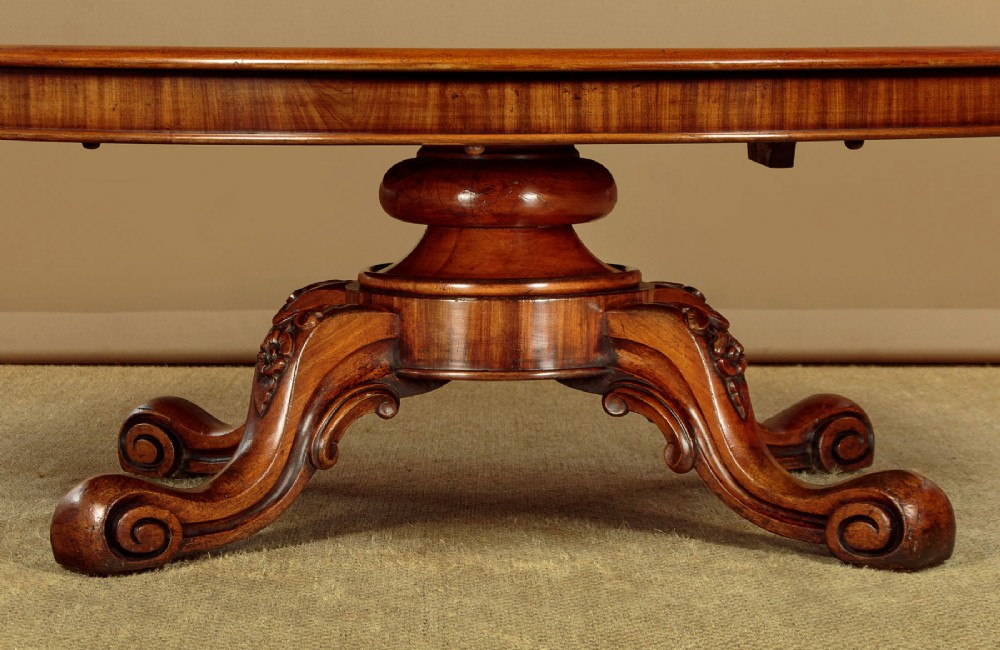 A large Victorian mahogany oval coffee table featuring a polished top, a deep apron, and a carved quadruped pedestal base with scroll feet. View IX