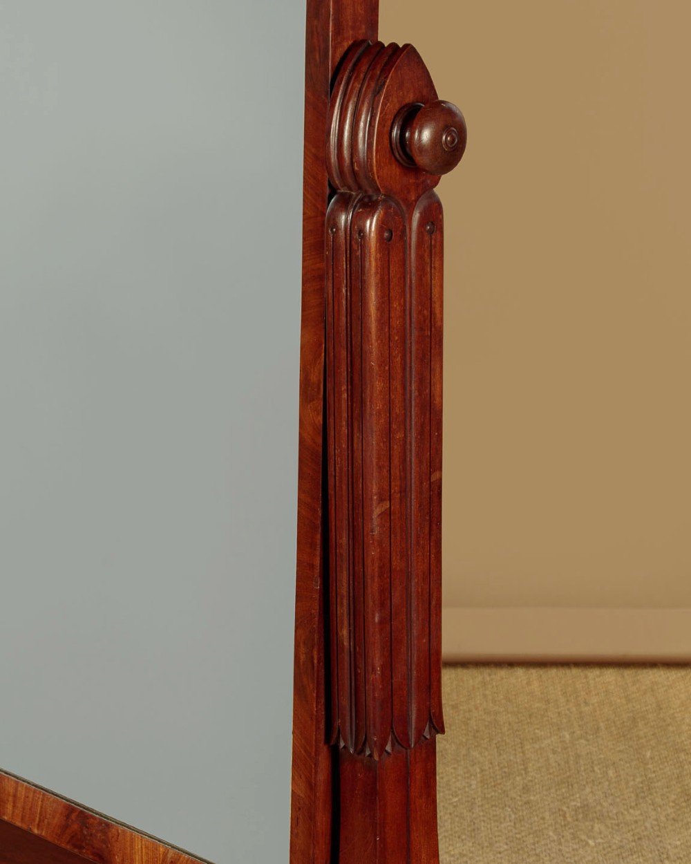 A 19th-century mahogany cheval mirror featuring a rectangular swivelling glass frame set between carved reeded uprights on scroll feet. View V