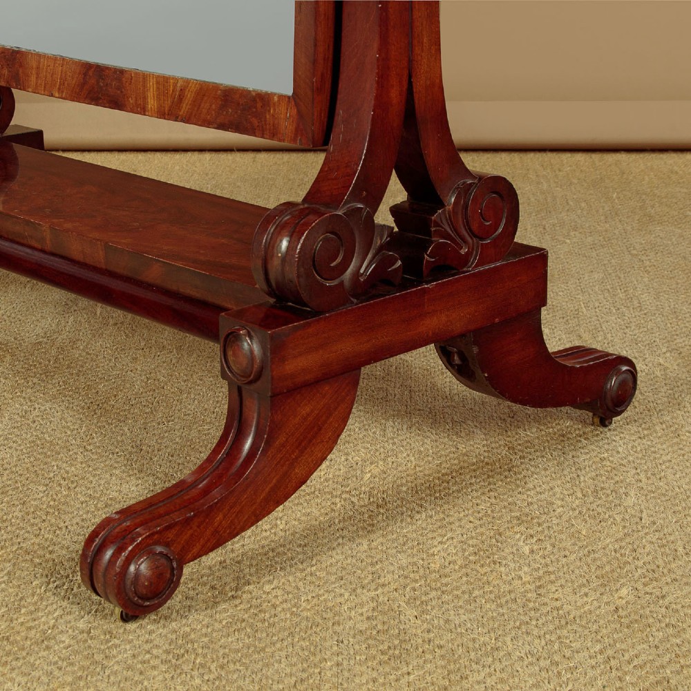 A 19th-century mahogany cheval mirror featuring a rectangular swivelling glass frame set between carved reeded uprights on scroll feet. View VII