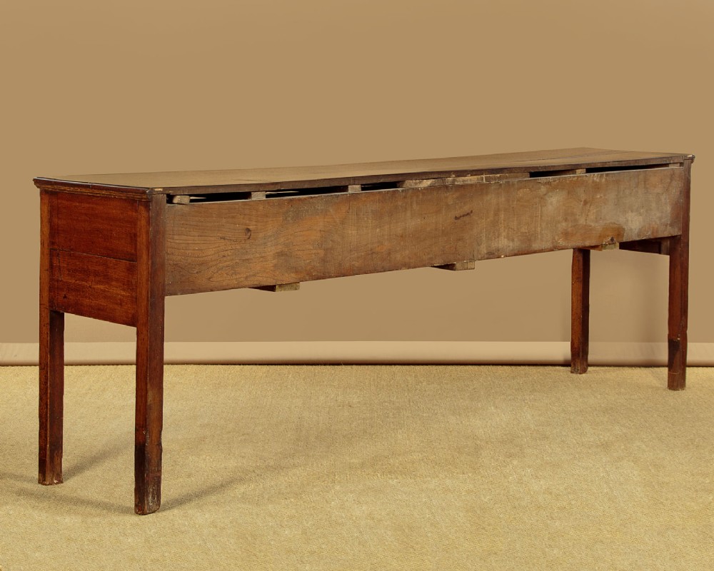 An 18th-century long oak dresser base featuring four drawers with brass swan-neck handles, a scalloped lower apron, and straight square legs. View X