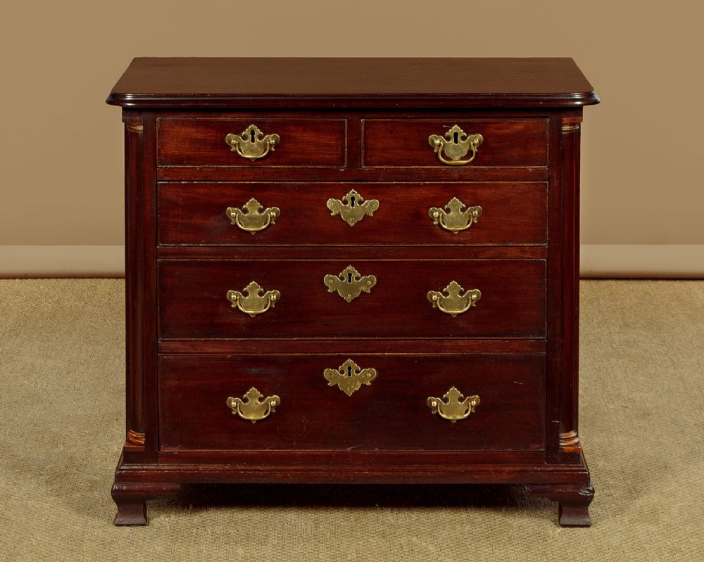 A small Georgian mahogany chest of drawers featuring two short and three long graduated drawers with brass batwing backplate handles and bracket feet.