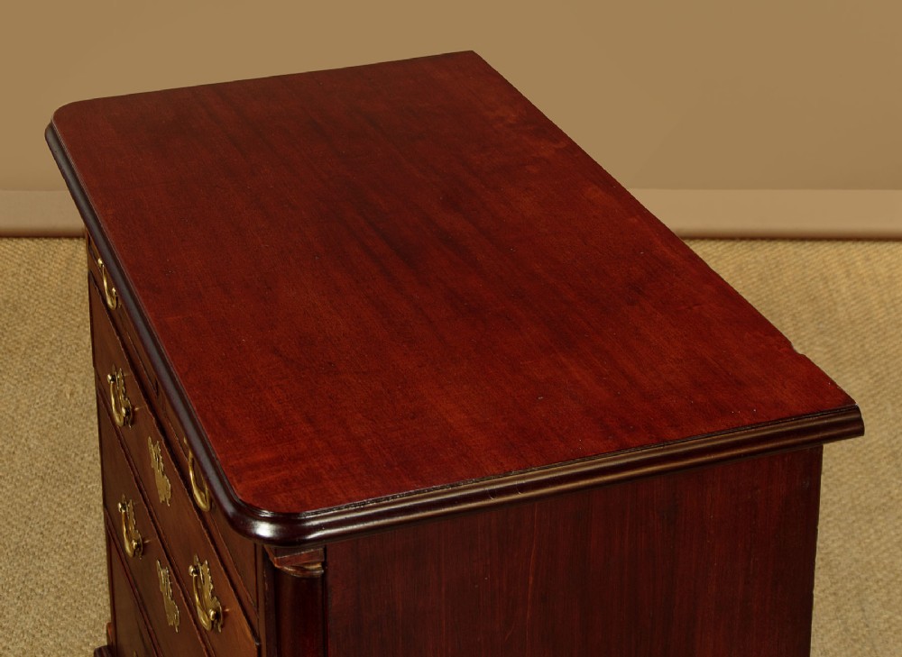 A small Georgian mahogany chest of drawers featuring two short and three long graduated drawers with brass batwing backplate handles and bracket feet. View V