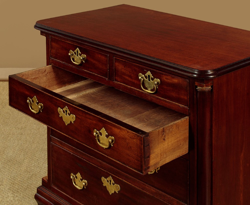 A small Georgian mahogany chest of drawers featuring two short and three long graduated drawers with brass batwing backplate handles and bracket feet. View VI