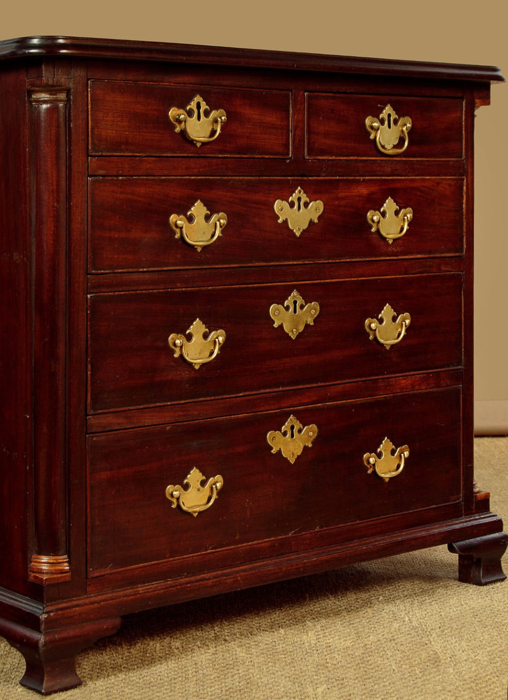 A small Georgian mahogany chest of drawers featuring two short and three long graduated drawers with brass batwing backplate handles and bracket feet. View VII