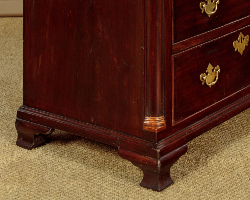 A small Georgian mahogany chest of drawers featuring two short and three long graduated drawers with brass batwing backplate handles and bracket feet. View X