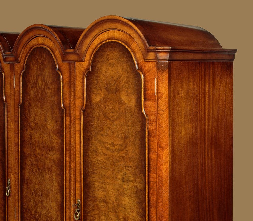 A 1920s Queen Anne style triple-door combination wardrobe made of figured burr walnut veneer with triple arched cornices and cabriole legs. View V