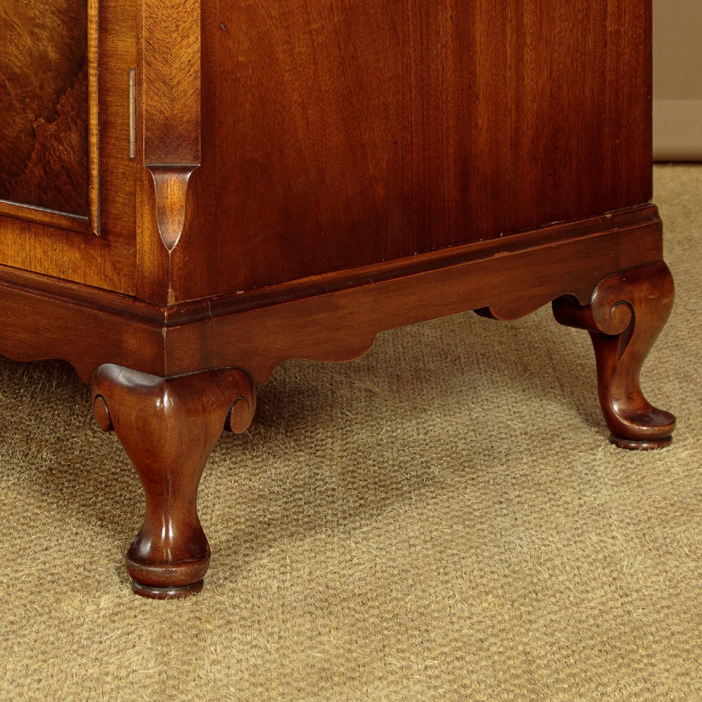 A 1920s Queen Anne style triple-door combination wardrobe made of figured burr walnut veneer with triple arched cornices and cabriole legs. View X