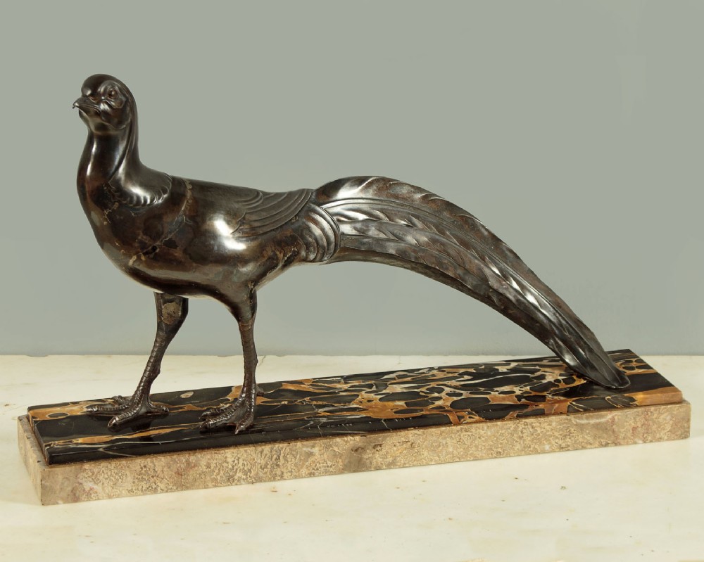 An Art Deco patinated metal sculpture of a long-tailed pheasant mounted on a rectangular black and gold marbled base.