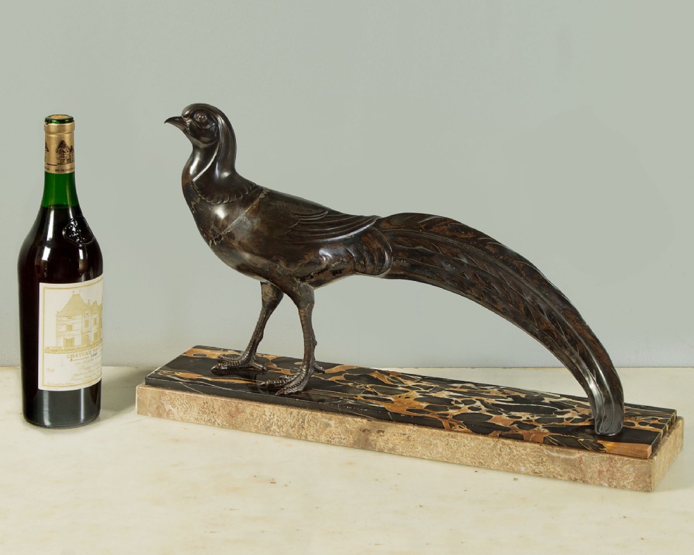 An Art Deco patinated metal sculpture of a long-tailed pheasant mounted on a rectangular black and gold marbled base. View II