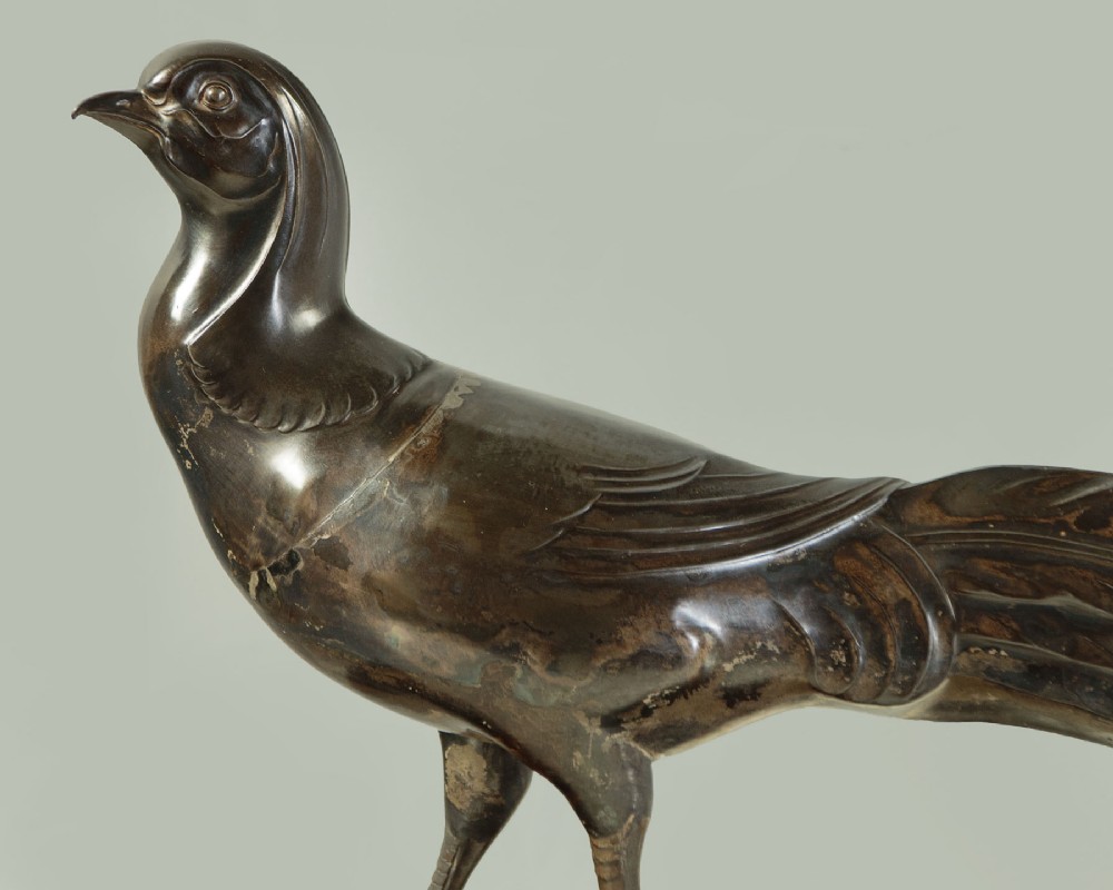 An Art Deco patinated metal sculpture of a long-tailed pheasant mounted on a rectangular black and gold marbled base. View VI