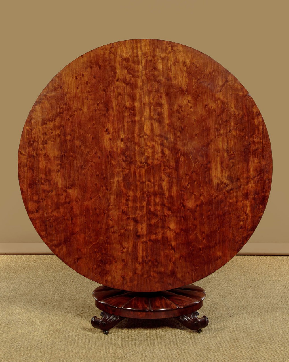 An early Victorian circular mahogany breakfast table with a central pedestal and lobed base supported by scroll feet on brass castors. View III