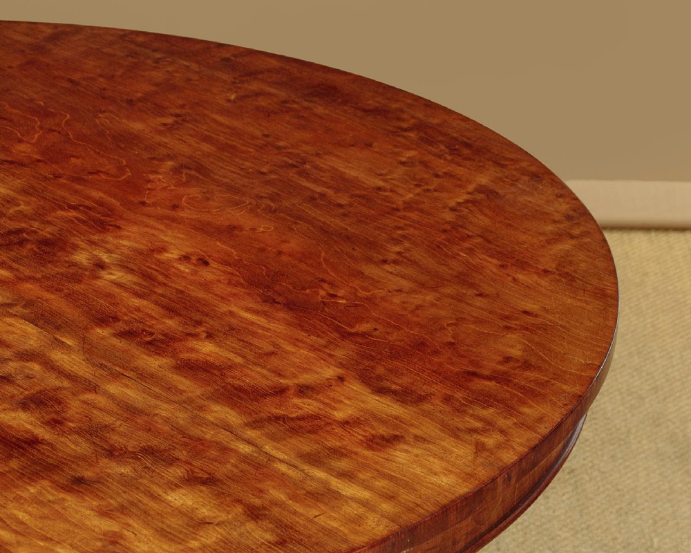 An early Victorian circular mahogany breakfast table with a central pedestal and lobed base supported by scroll feet on brass castors. View V