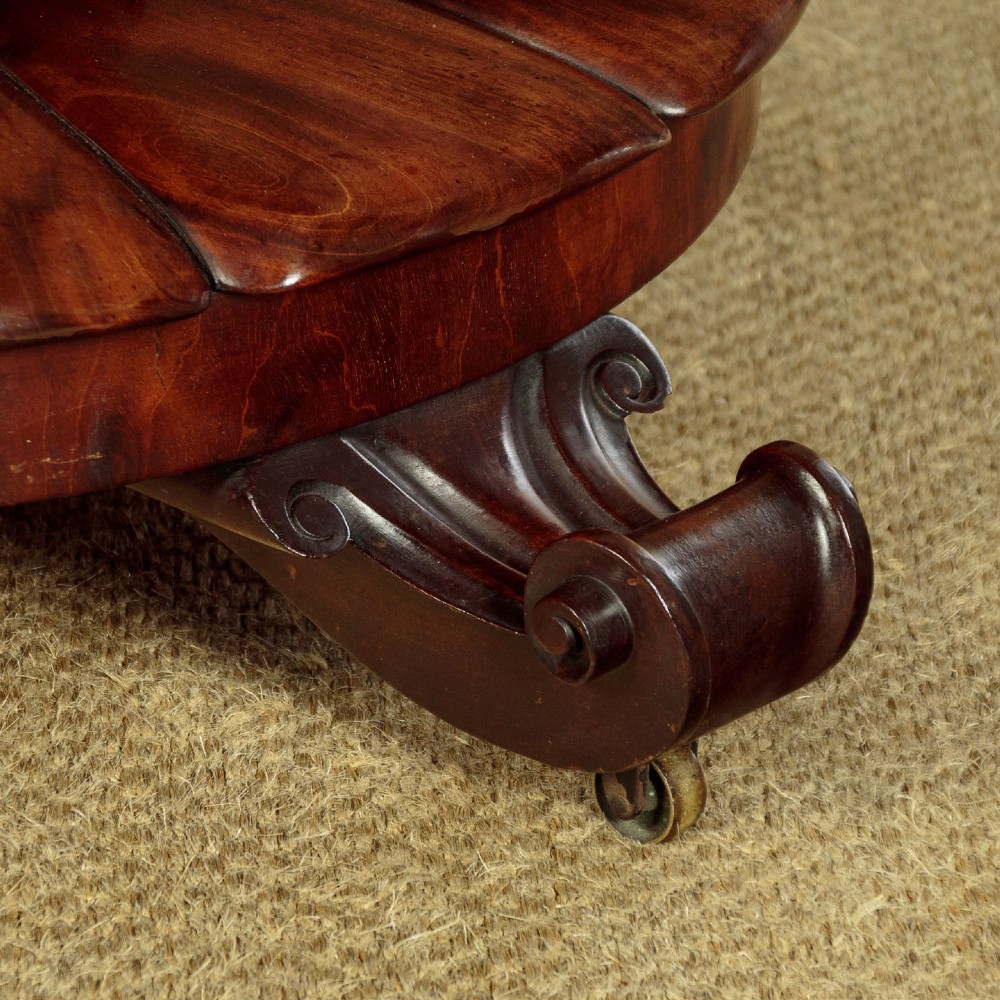 An early Victorian circular mahogany breakfast table with a central pedestal and lobed base supported by scroll feet on brass castors. View VIII