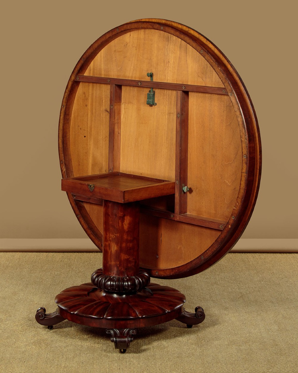 An early Victorian circular mahogany breakfast table with a central pedestal and lobed base supported by scroll feet on brass castors. View X
