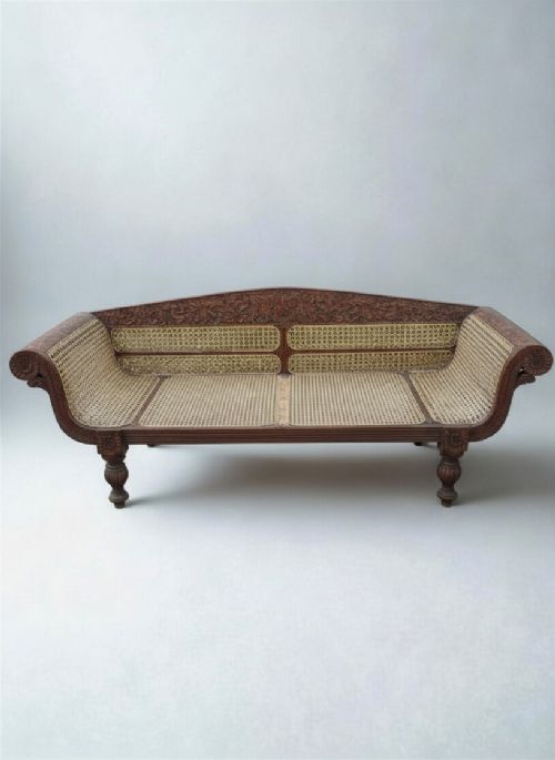 fig 1. A 19th-century Anglo-Indian carved hardwood daybed featuring woven cane back and seat panels with scroll arms and turned legs.