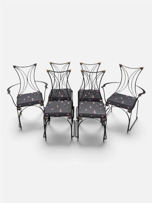 fig 1. A set of six black wrought iron dining chairs featuring curved hourglass backrests, brass accents, and dark upholstered cushion seats.
