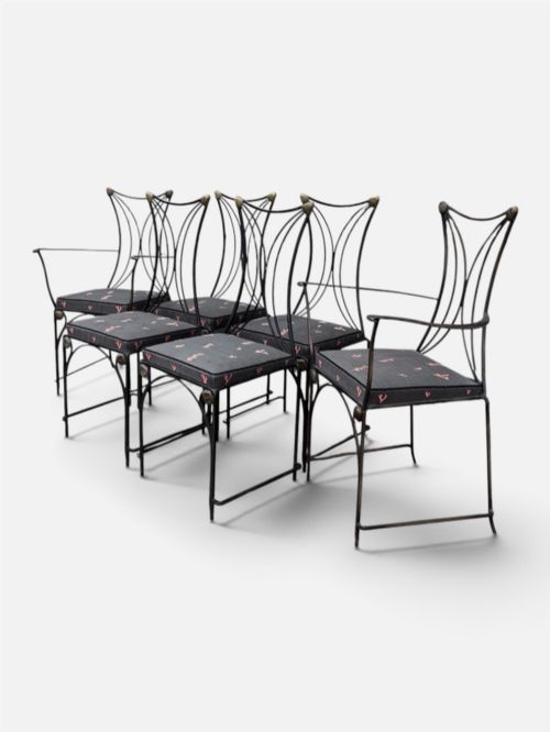 fig 2. A set of six black wrought iron dining chairs featuring curved hourglass backrests, brass accents, and dark upholstered cushion seats.