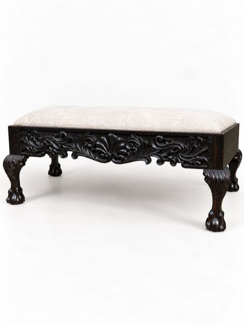 fig 1. A 19th-century Ceylonese calamander wood stool featuring detailed floral relief carvings on the frame, cabriole legs with claw-and-ball feet, and neutral upholstered seat.