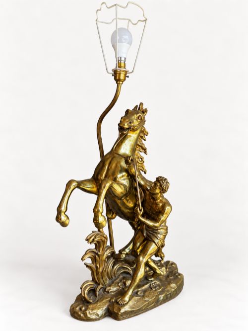fig 2. A sculptural brass table lamp depicting a rearing horse and groom after Guillaume Coustou, topped with a tall cylindrical gold leaf drum shade.