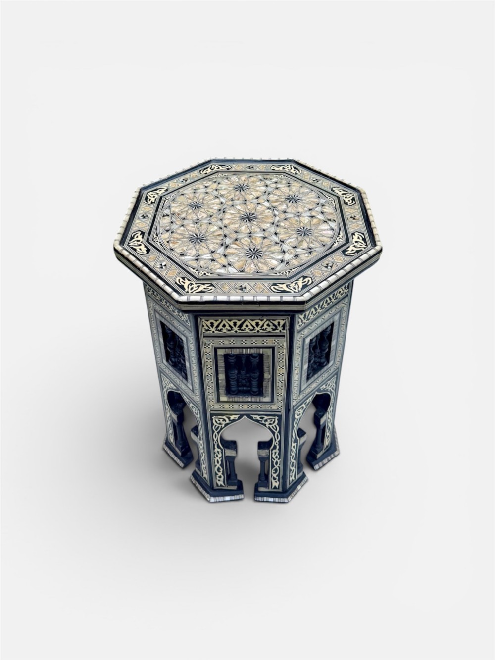 A 19th-century octagonal side table constructed from dark wood intricately inlaid with geometric mother-of-pearl star patterns and arched apron motifs.