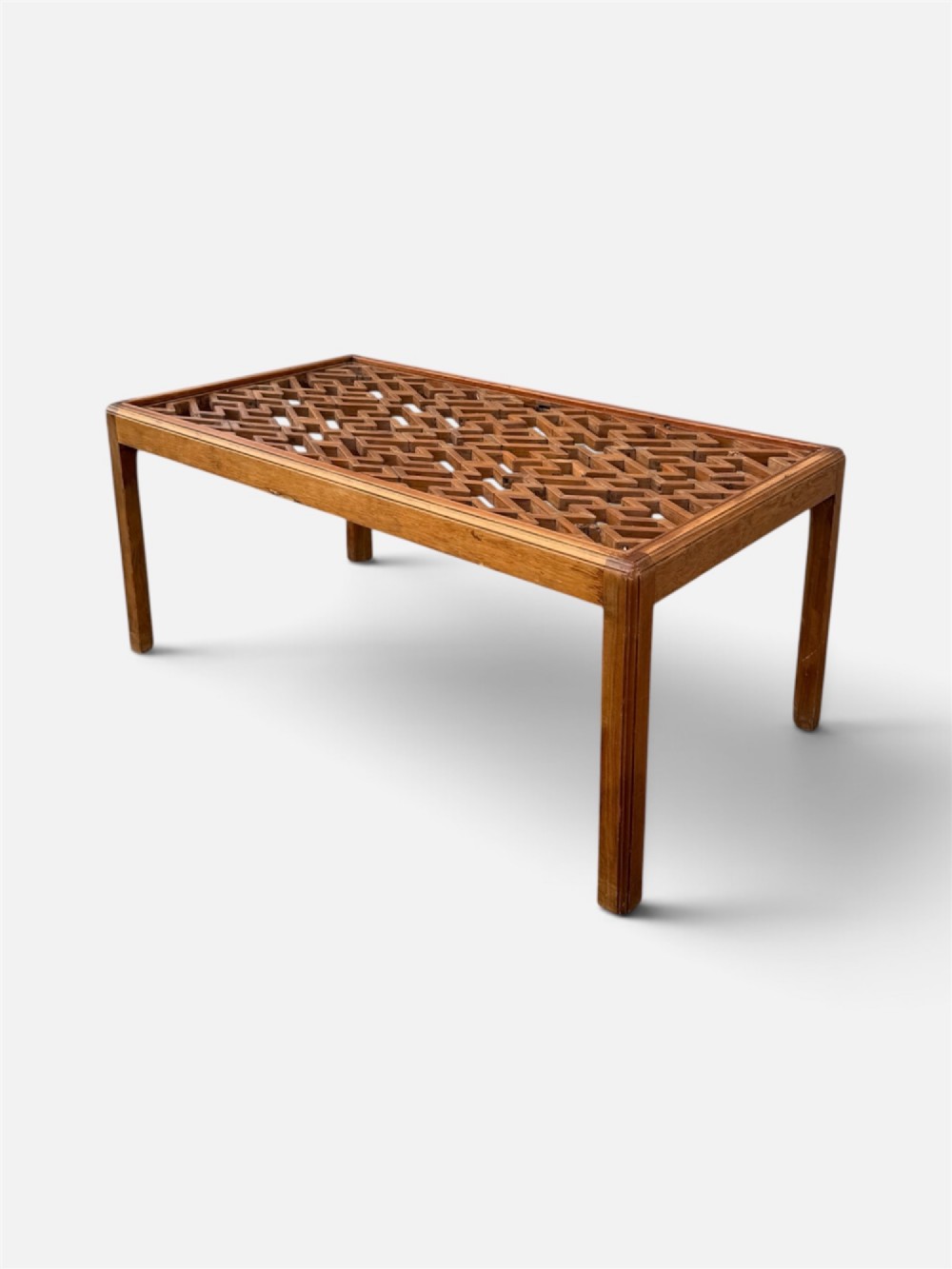 A rectangular low coffee table crafted from warm brown wood featuring an intricate geometric Chinese fretwork panel set beneath a clear glass top.