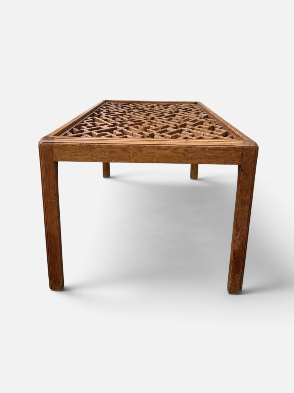 A rectangular low coffee table crafted from warm brown wood featuring an intricate geometric Chinese fretwork panel set beneath a clear glass top. View III