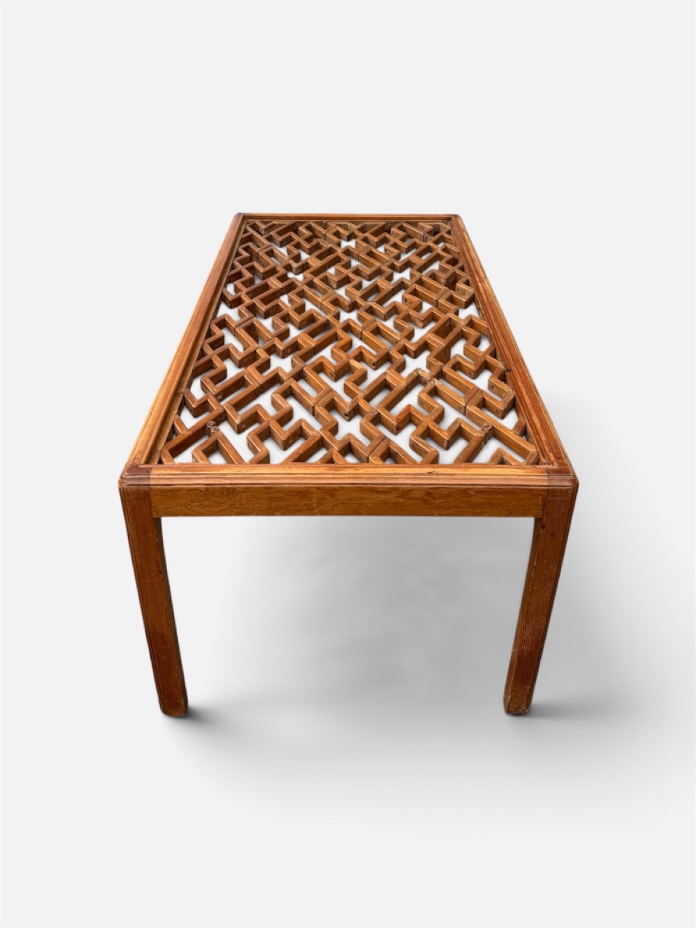 A rectangular low coffee table crafted from warm brown wood featuring an intricate geometric Chinese fretwork panel set beneath a clear glass top. View IV