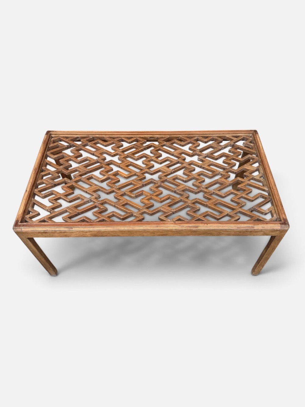 A rectangular low coffee table crafted from warm brown wood featuring an intricate geometric Chinese fretwork panel set beneath a clear glass top. View V