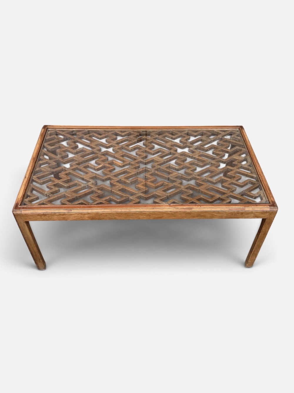 A rectangular low coffee table crafted from warm brown wood featuring an intricate geometric Chinese fretwork panel set beneath a clear glass top. View VIII