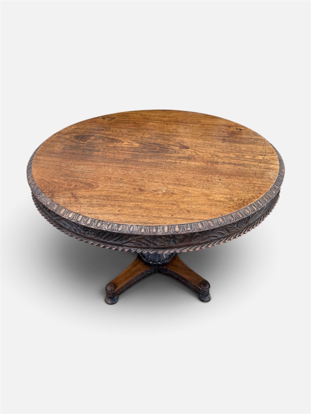 A 19th-century circular Anglo-Indian rosewood centre table featuring a carved foliate frieze, turned pedestal support, and a four-point carved platform base. View III