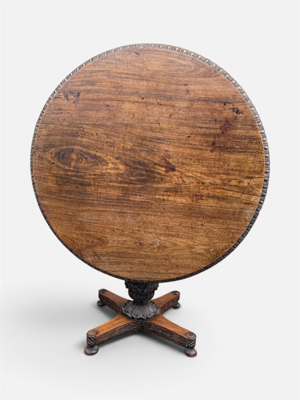 A 19th-century circular Anglo-Indian rosewood centre table featuring a carved foliate frieze, turned pedestal support, and a four-point carved platform base. View VI