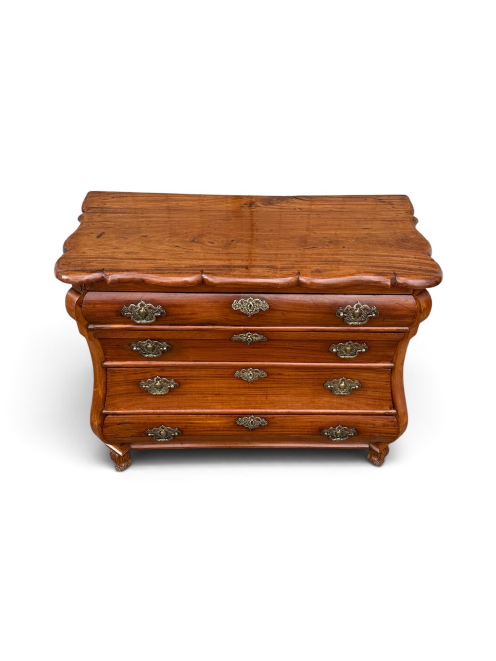 An 18th-century Dutch Colonial solid satinwood bombe chest featuring four graduated drawers, ornate brass handles, and carved feet. View II