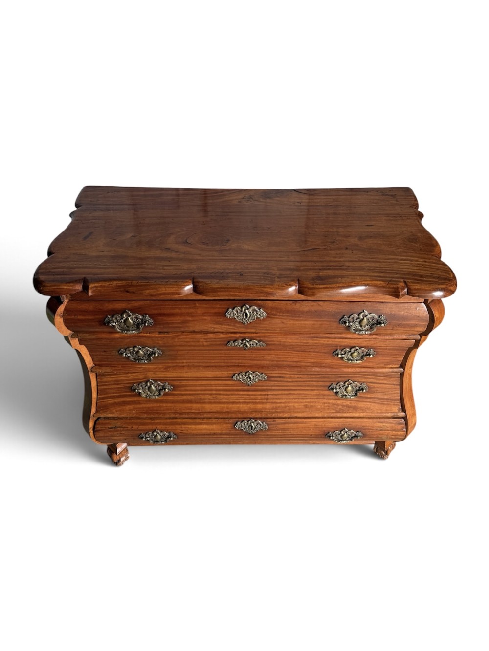 An 18th-century Dutch Colonial solid satinwood bombe chest featuring four graduated drawers, ornate brass handles, and carved feet. View III